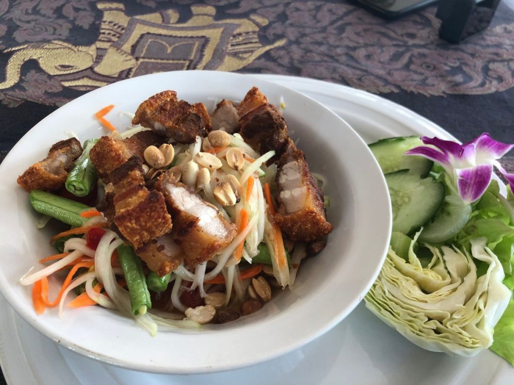 plate with papaya salad and crispy pork