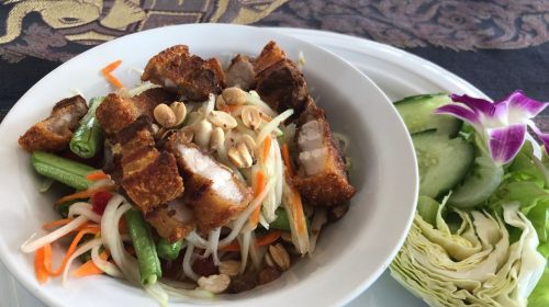 plate with papaya salad and crispy pork