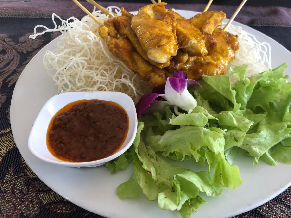 plate with chicken satay, noodles and sauce